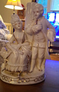 Porcelain figurine depicting a Victorian courting couple in white with gold...