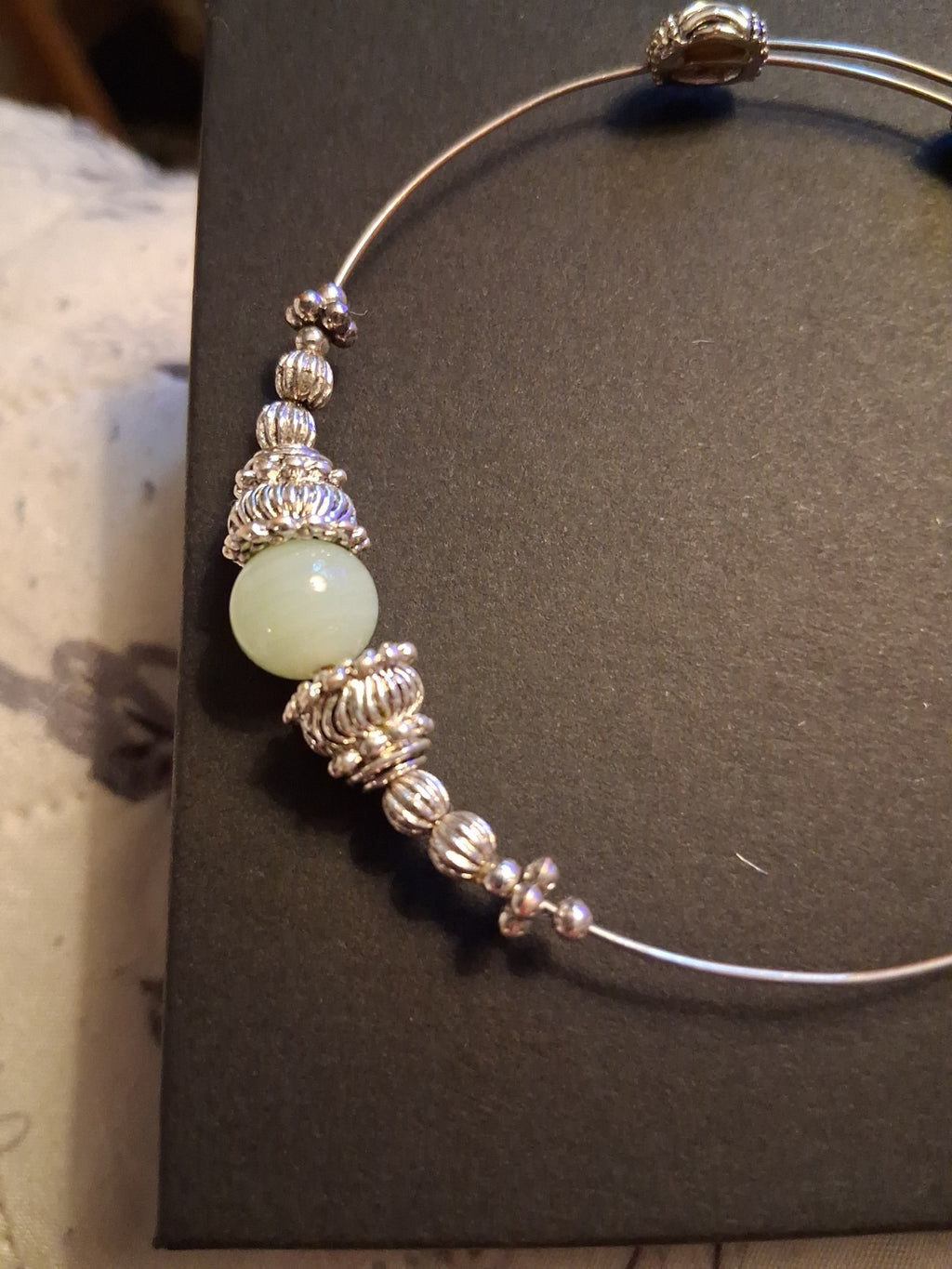 Silver-tone bangle bracelet with decorative beads and pale green stone