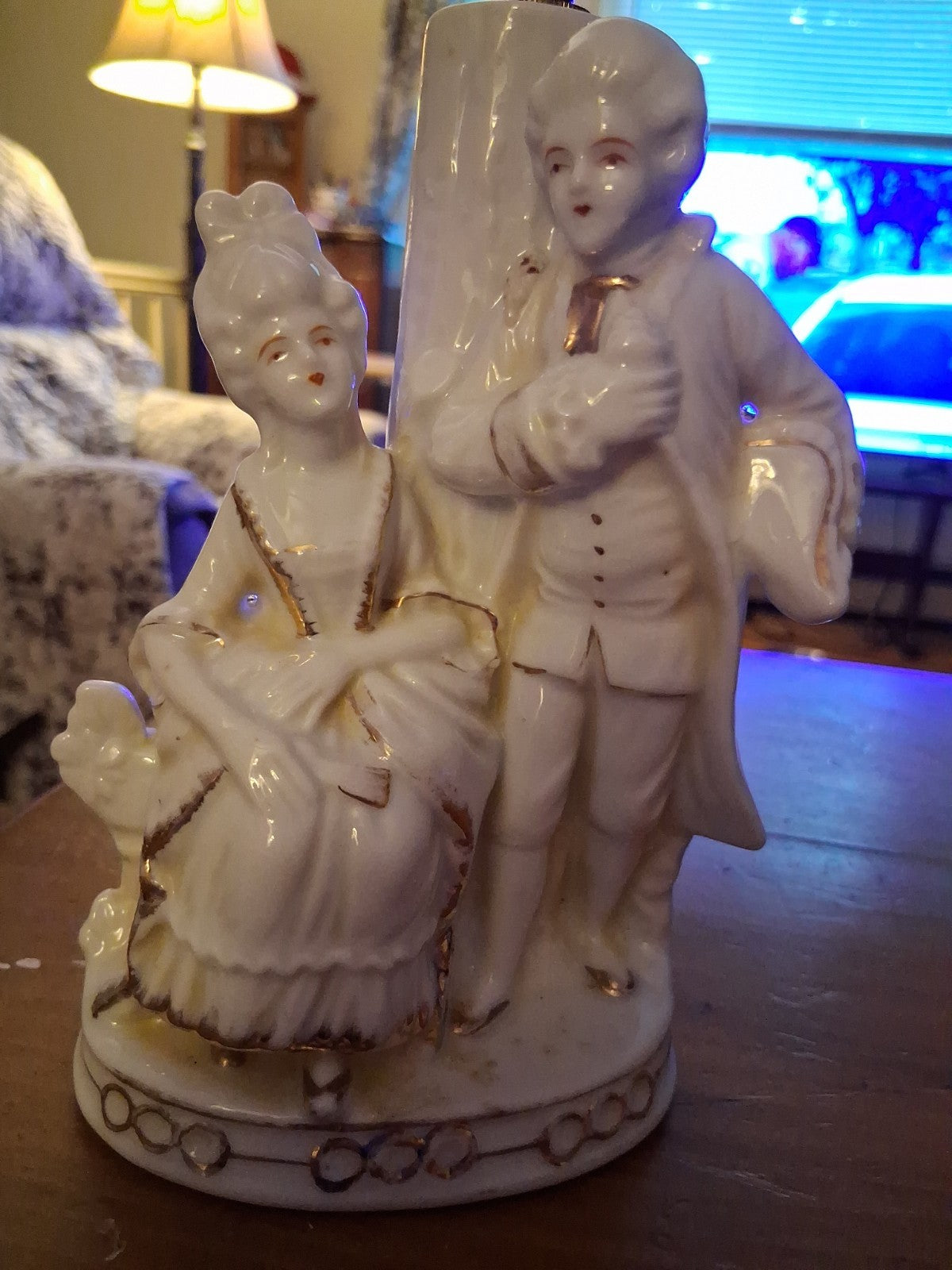 Porcelain figurine depicting a Victorian courting couple in white with gold...