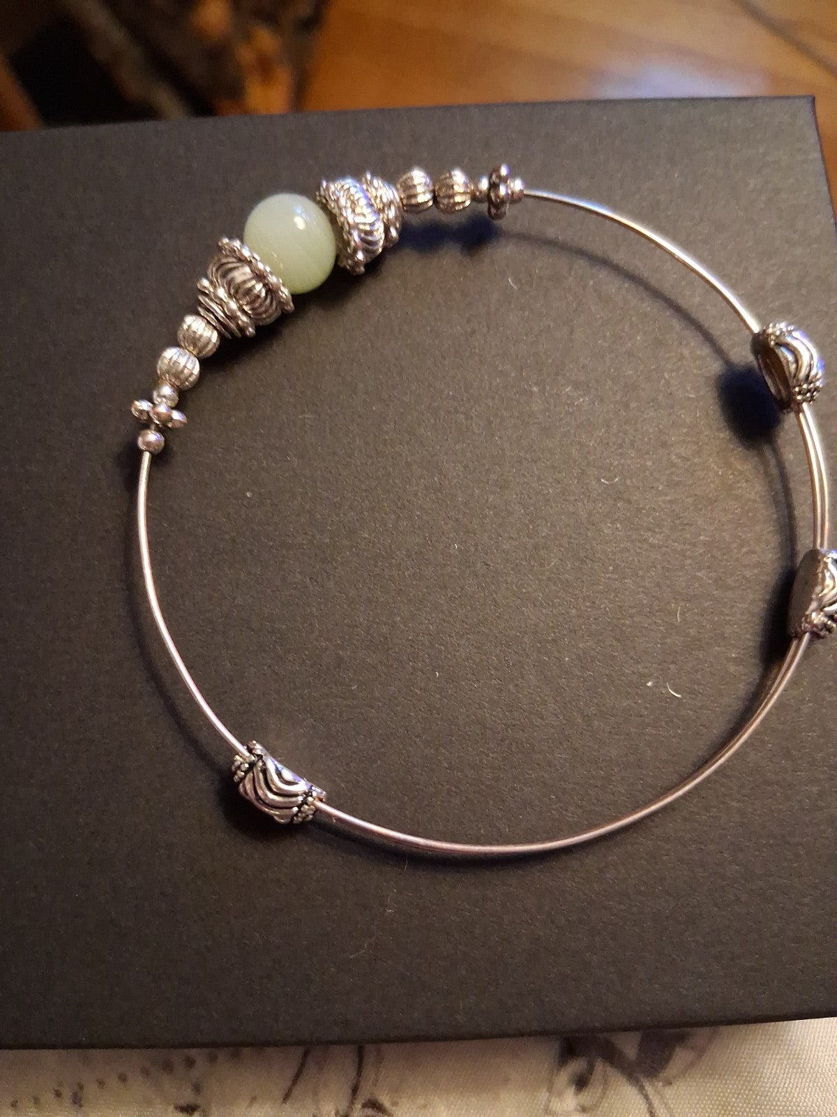 Silver-tone bangle bracelet with decorative beads and pale green stone