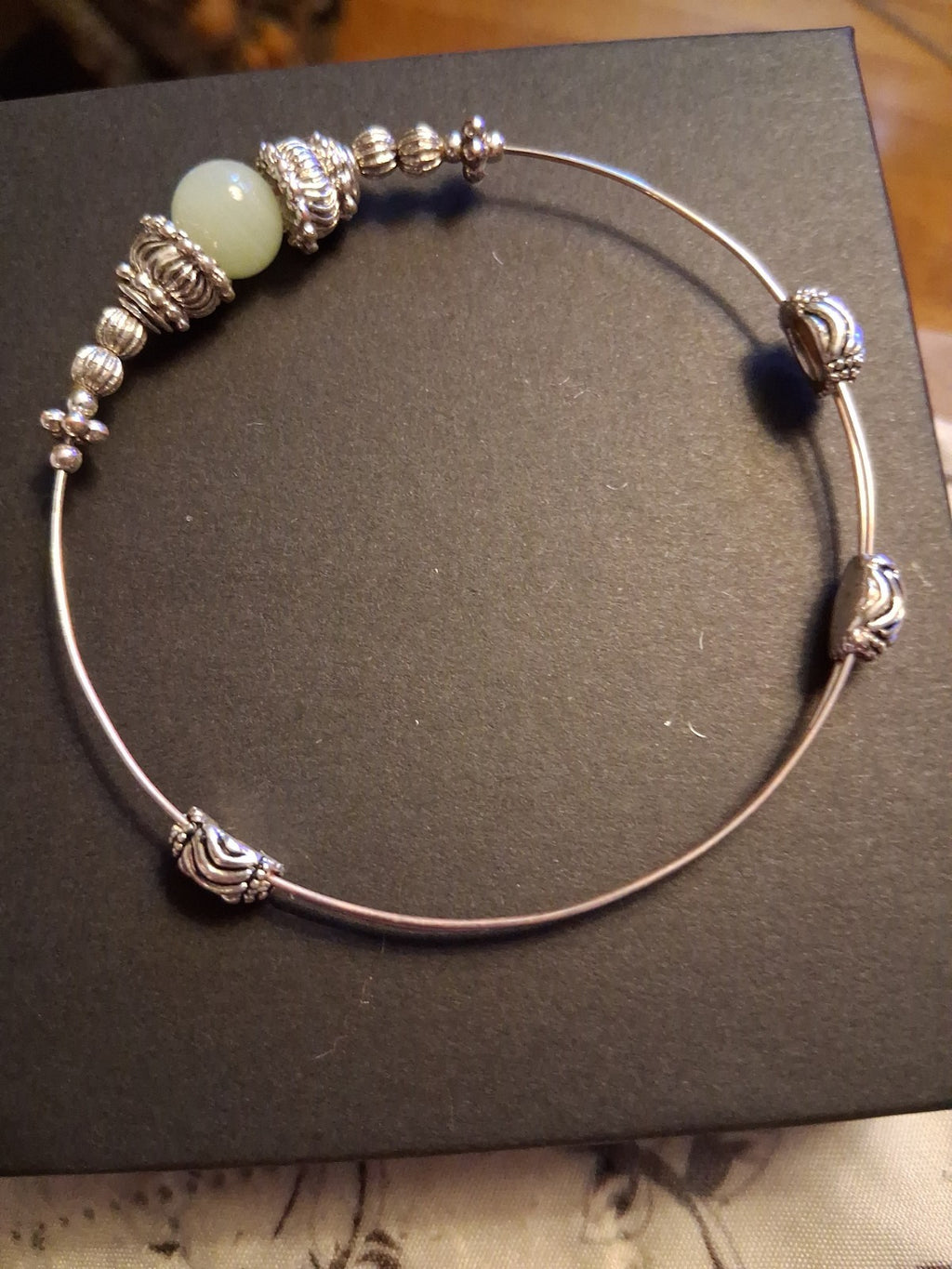 Silver-tone bangle bracelet with decorative beads and pale green stone