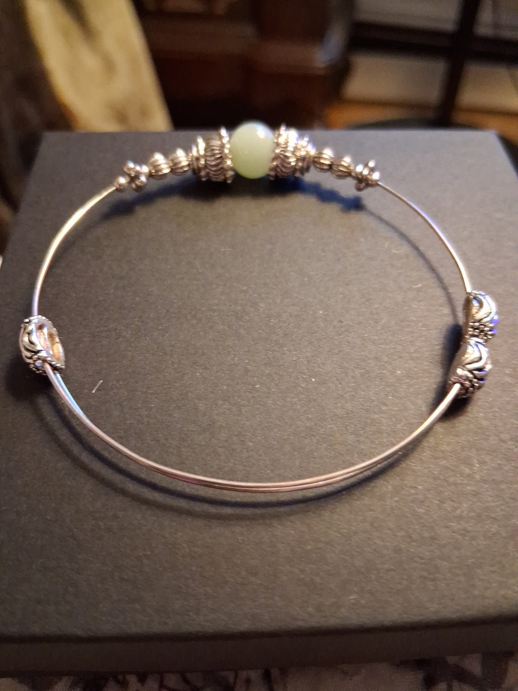 Silver-tone bangle bracelet with decorative beads and pale green stone