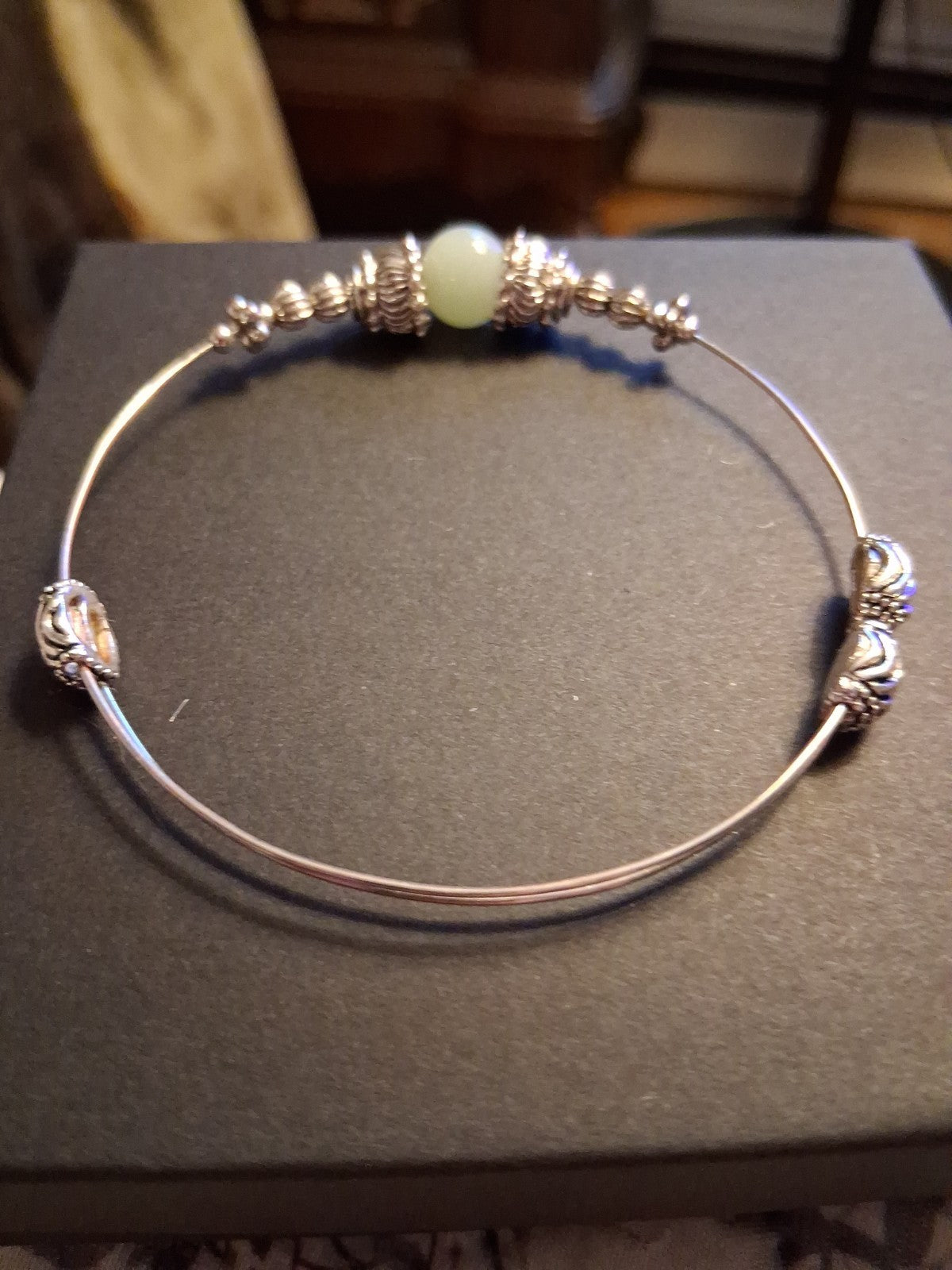 Silver-tone bangle bracelet with decorative beads and pale green stone
