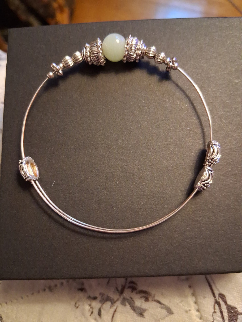 Silver-tone bangle bracelet with decorative beads and pale green stone