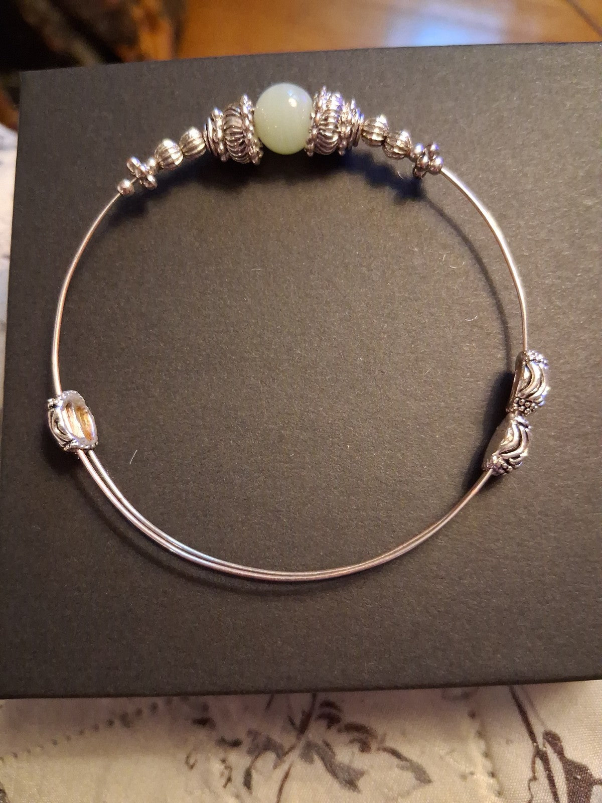 Silver-tone bangle bracelet with decorative beads and pale green stone