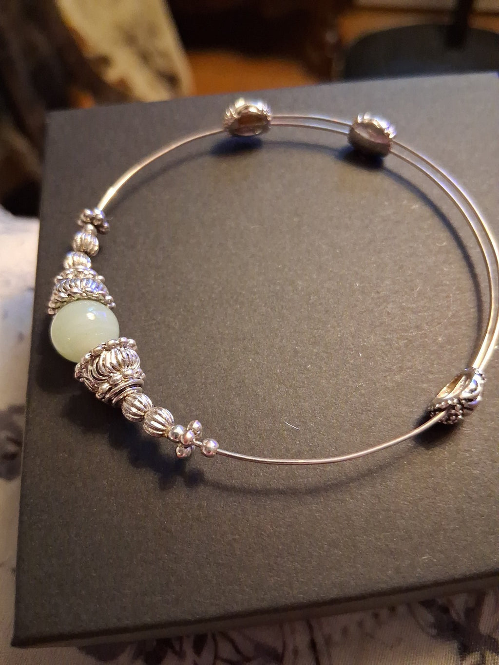 Silver-tone bangle bracelet with decorative beads and pale green stone