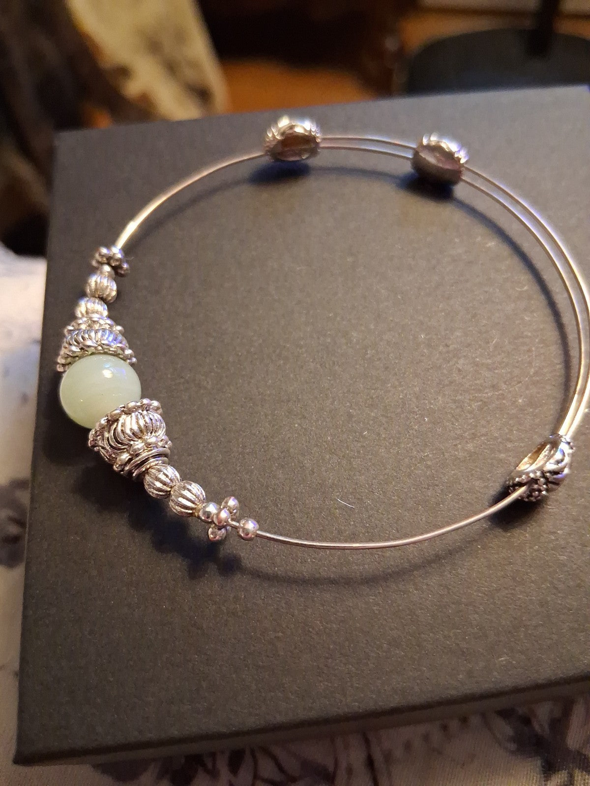 Silver-tone bangle bracelet with decorative beads and pale green stone